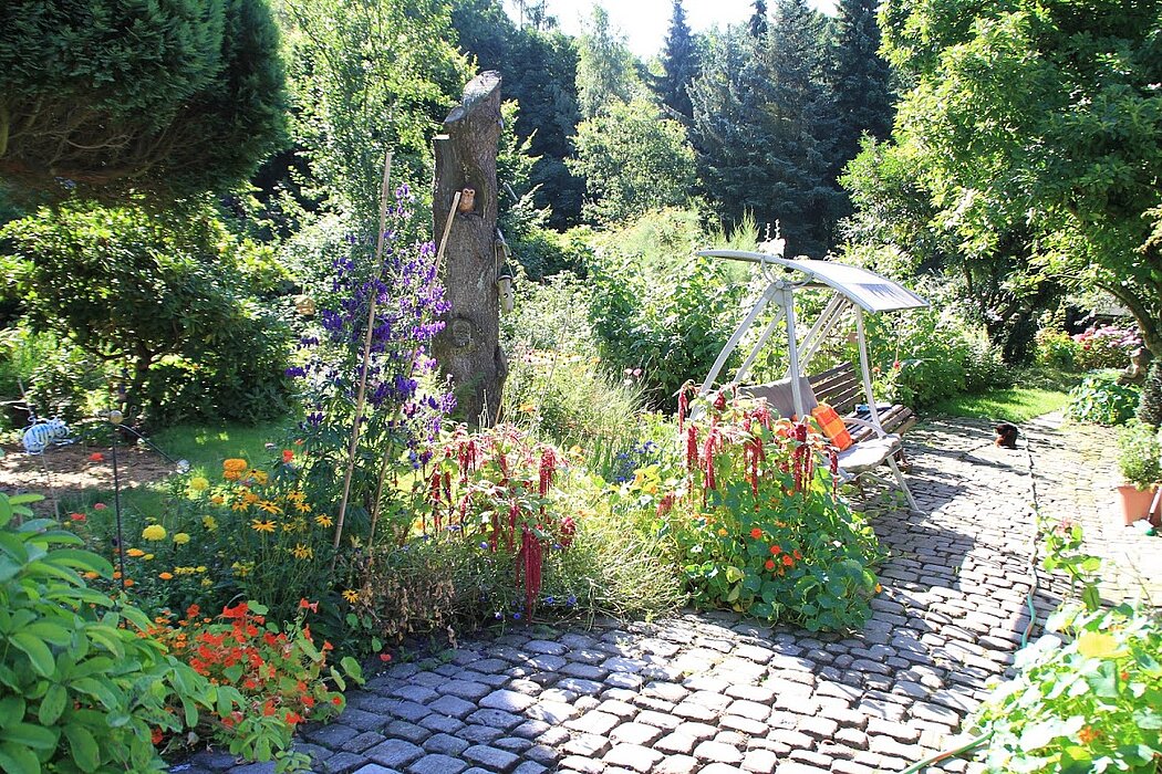 Ruheplatz am blütenumsäumten Gartenweg