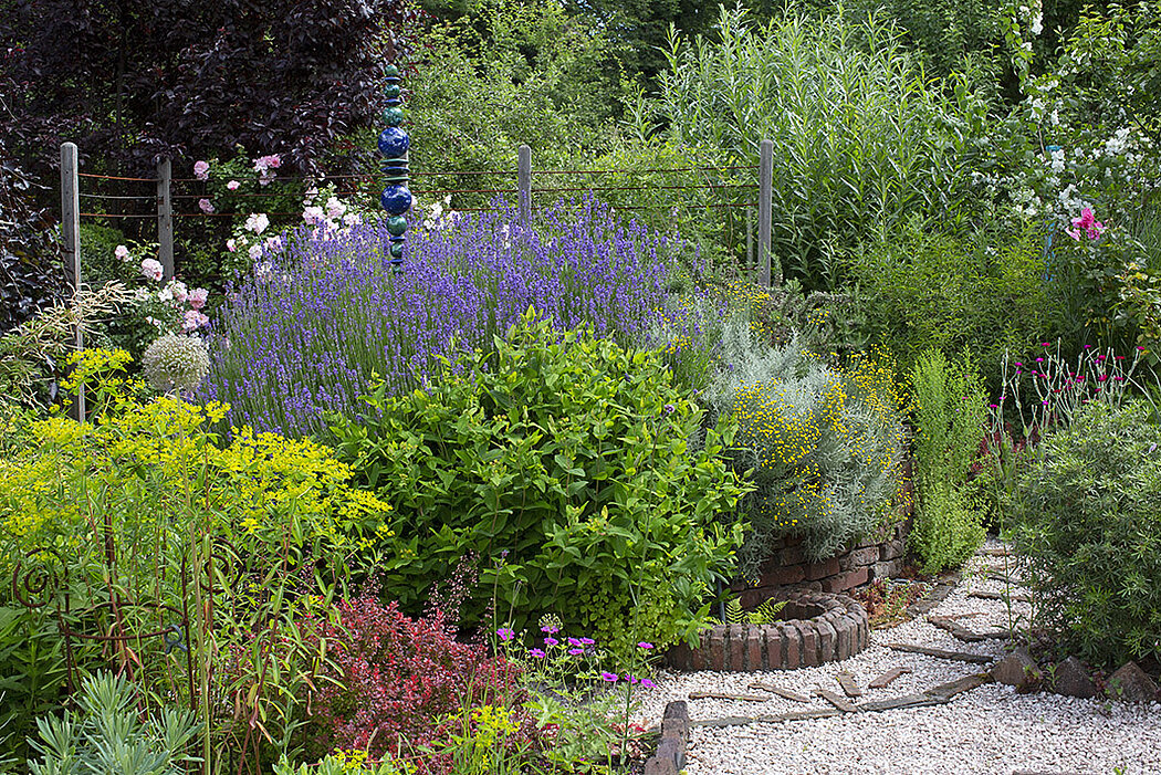 üppig bepflanzte Blumenspirale mit Lavendel, Johanniskraut und vielen bunten Stauden