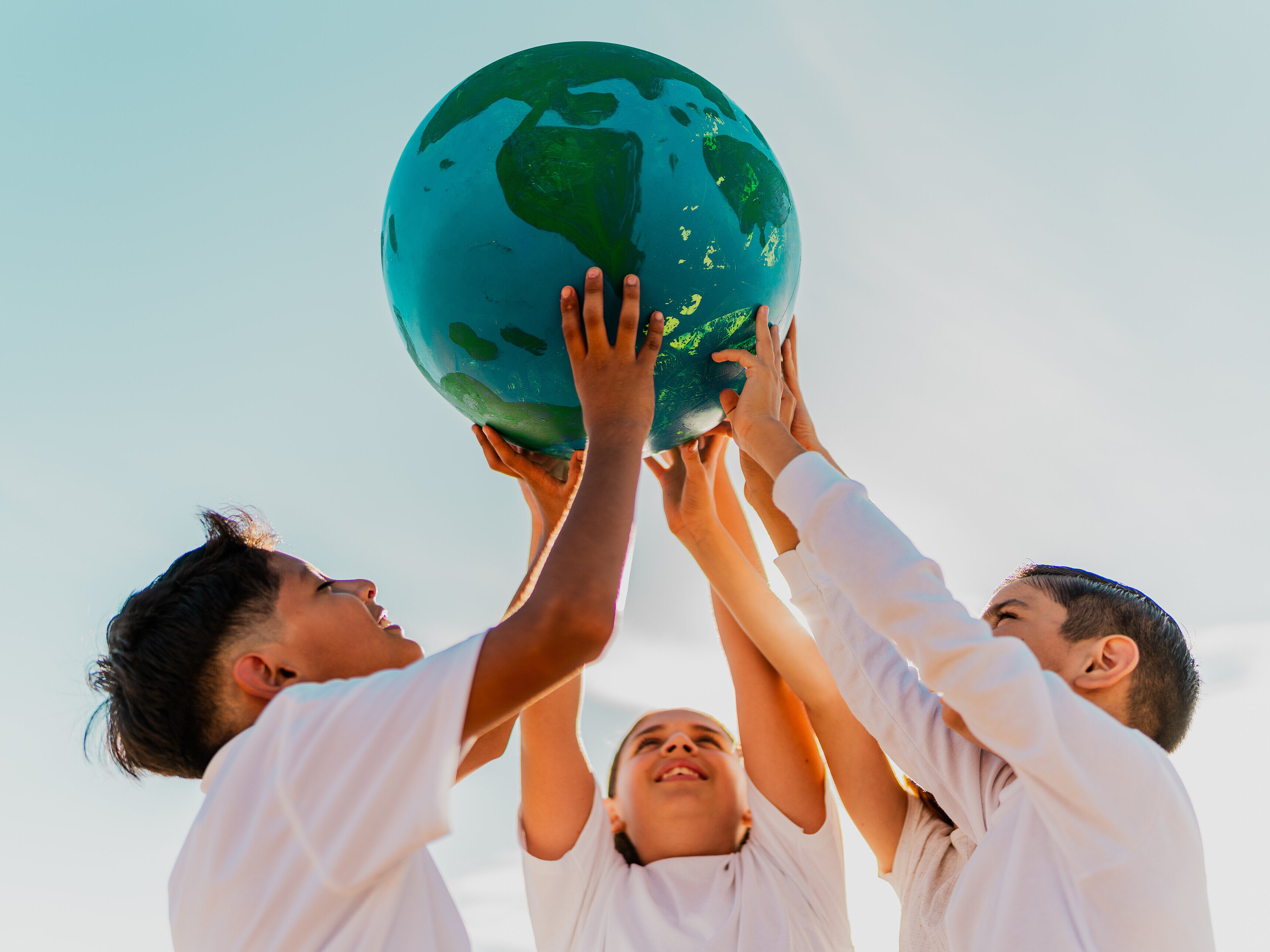 Kinder halten einen Globus hoch