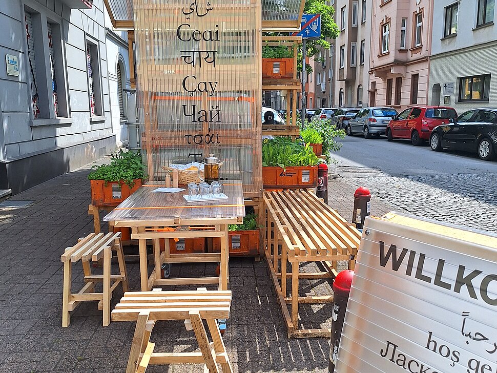 Außenbereich des Pop-Up-IGA Duisburg-Hochfeld mit Tisch, zwei Hockern und Infomaterial