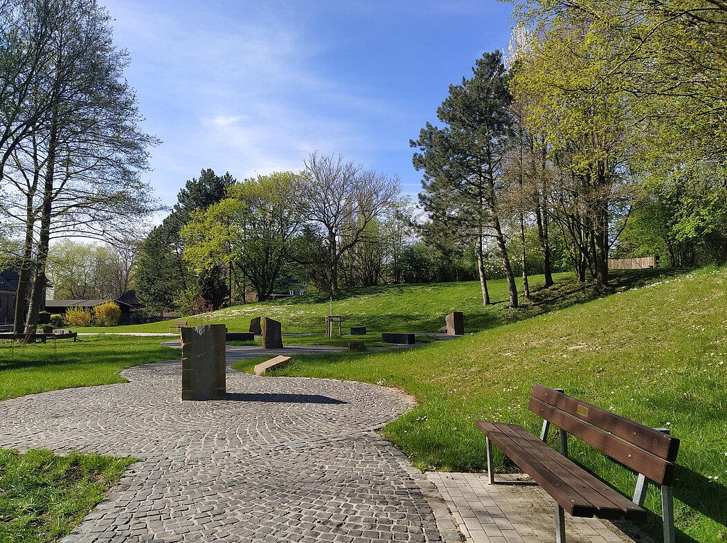 Blick in den Garten mit Steinstelen und Bänken