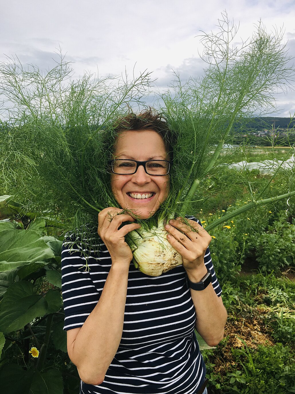 Eine Frau, die durch das Grün einer Fenchelknolle schaut
