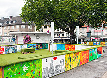 Das Foto zeigt den Gemarkenplatz in der Stadt Essen, auf dem eine farbenfrohe Installation aufgebaut wurde. 