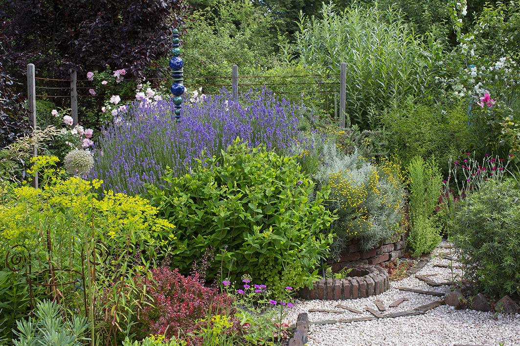 üppig bepflanzte Blumenspirale mit Lavendel, Johanniskraut und vielen bunten Stauden