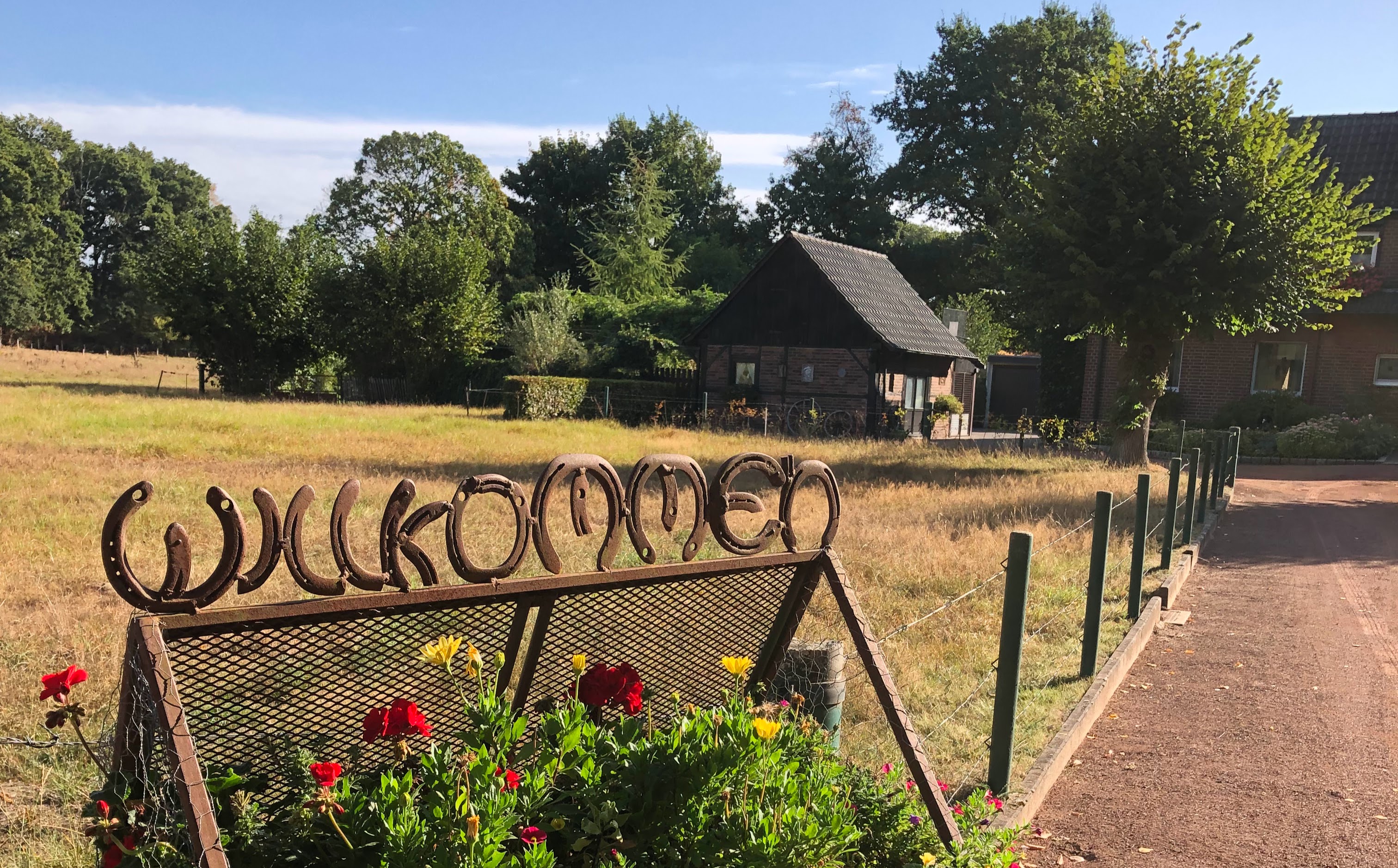 Willkommensschild aus Hufeisen mit Blick auf das Fachwerkhäuschen.
