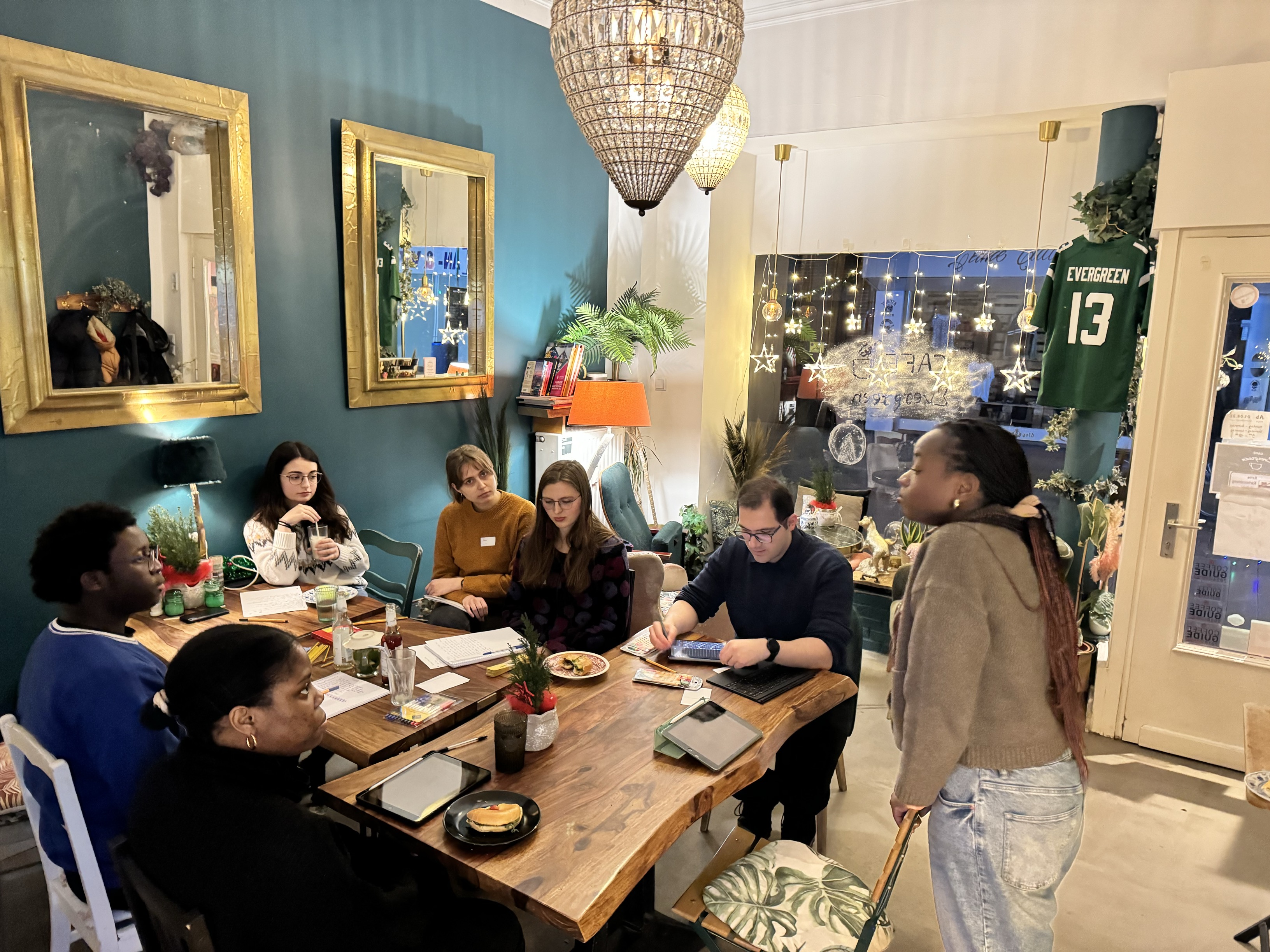 Mehrere Personen sitzen in einem Café an einem Tisch und arbeiten im Rahmen eines Workshops zu kreativem Schreiben an ihren Texten